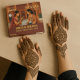 Mains de femme décorées de motifs au henné avec la boîte Sansar Special Dulhan posée sur une table