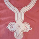 Finition du col traditionnel sur une djellaba femme en tissu gaufré rose.