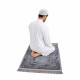 Tapis de prière gris avec homme assis en prière